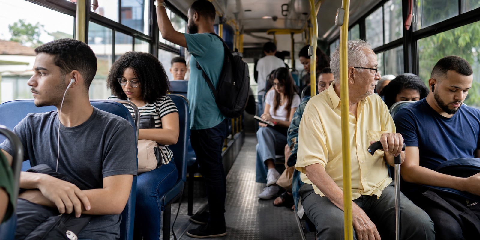 Passageiros dentro de ônibus urbano, com pessoas de diferentes idades usando o transporte cotidiano.
